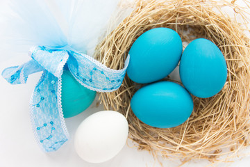 Blue colored Easter eggs in nest on wooden background, selective focus image. Happy Easter card 