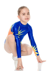 Beautiful little girl gymnast is squatting.
