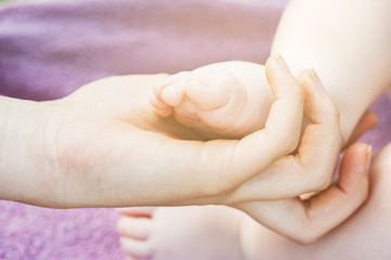 Baby feet in mother hands. Tiny newborn baby feet, concept of happy family. Fake color tone of photo..