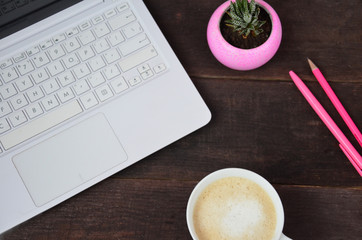 Office table with laptop, pencils and a Cup of coffee. The view from the top