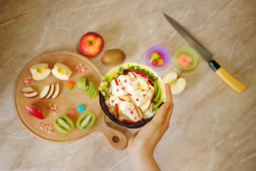 Завтрак из фруктов. Фруктовый десерт с мороженым. Киви и яблоко на кухонной круглой деревянной доске. Ломтики фруктов. Здоровая пища. Полезные сладости.
