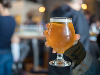 Hand holding a light beer snifter in bar/brewery