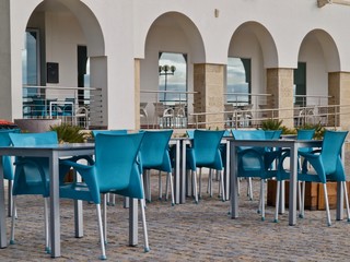 Typisches Cafe am Strand mit blauen Stuehlen 