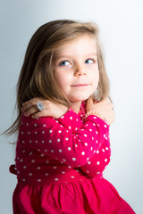 Bambina bionda con sguardo da furbetta e abito rosa a pallini bianchi