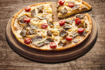 Hot pizza slice with melting cheese on a rustic wooden table.