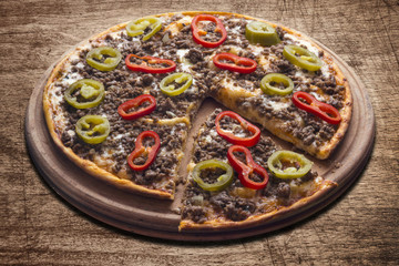 Hot pizza slice with melting cheese on a rustic wooden table.
