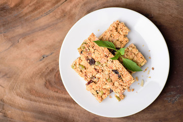Snack bar or energy bar on white dish and wooden background, top view