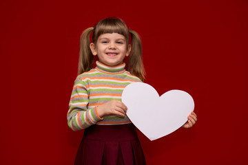 Portrait of cheerful little girl isolated on red hold white paper heart