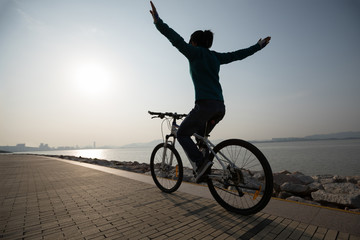 Fototapeta premium silhouette cyclist riding bike in the sunrise coast road