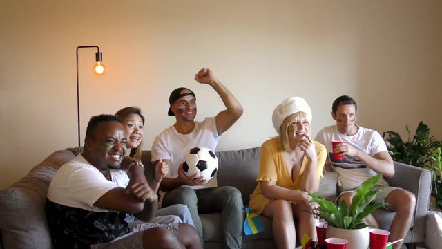 Multinational sports fans watching football on TV with cheer and excitement. Slider shot