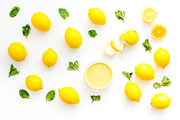 Lemon curd in bowl among lemons on white background top view