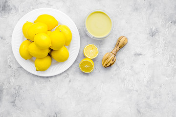 Lemon curd. Sweet cream for desserts near lemons and juicer on grey background top view copy space