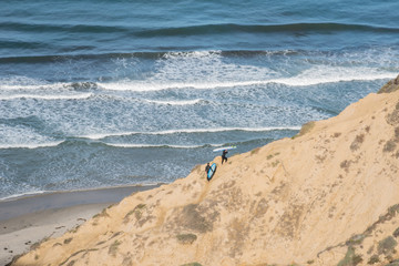 Surfers climb the cliffs up from the beach after catching some waves