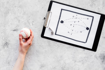 Sport coach concept. Pad with tactic plan of the match near whistle and base-ball ball on stone...