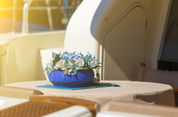 blue pot with the bright roses on the table of the yacht. depth of field blur