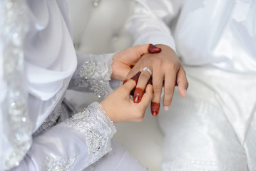 Obraz na płótnie Canvas malay wedding groom bolstering gold ring on bride's finger