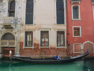 traditional gondola moored at the entrance of a palace in a canal in Venice, Italy. © gpriccardi