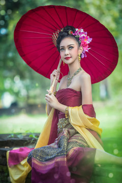 Thai woman dressing traditional costume holding red umbrella