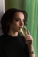 beautiful cheerful woman drinks champagne green background