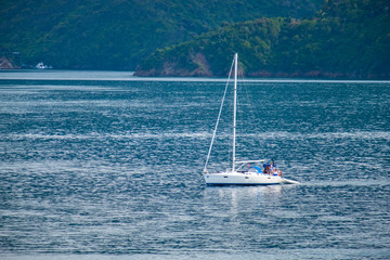 Obraz premium Group of people spend their holiday by fishing on a sailboat in the blue ocean and green nature.