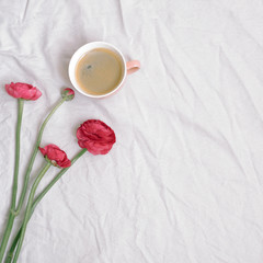 Obraz na płótnie Canvas Cup of coffee and pink anemone flowers on cotton sheet. Flat lay, top view, copy space