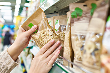 Hands with packaging of pine nuts in store