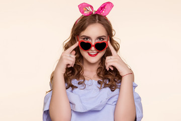 A beautiful young woman in the shape of a pin-up, adjusts the red glasses of the heart. On his head is a pink bandage, ears. The 14th of February.