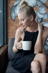 Pretty girl looking down and holding a cup of coffee