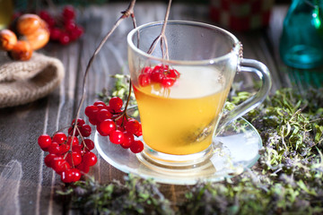 Still life with viburnum tea on sackcloth napkin, on wooden background