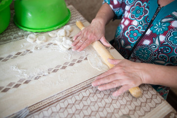 A woman rolls out the dough in the kitchen