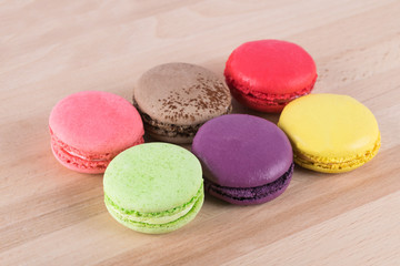 six colorful biscuits lie in two rows on a light wooden table