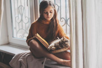 Child reading a book with cat