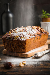 Cake sprinkled with powdered sugar. Baked with walnuts and dates. Wooden rustic table.