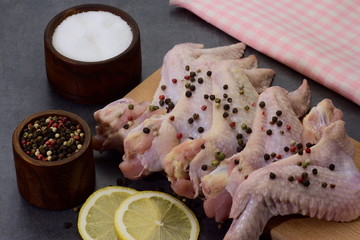 raw peppered and salted chicken wings on cutting board 