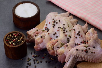 raw peppered and salted chicken wings on cutting board and lemon slices