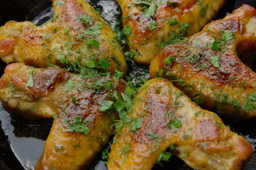 closeup of roasted chicken wings on a black pan