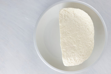 Cheese, soft cheese on a white plate, wooden table, black and white color, minimalism, Italian cuisine, rustic style, copy space, dairy product on a wooden board, Italian cuisine