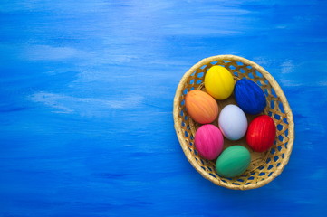 Easter eggs in yello basket on blue background S1V1