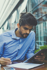 Business man working on digital tablet in street cafe. Businessman writing document.