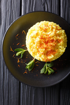 Italian risotto alla milanese with saffron closeup on a plate. Vertical top view from above