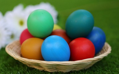 Fototapeta na wymiar Colors Easter eggs in basket on green blur background