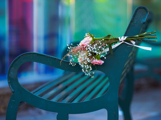 A memorial bouquet of flowers lying on a park bench
