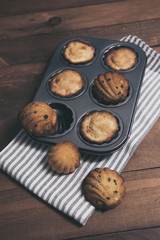 Homemade french madeleines with beurre noisette and chocolate on wooden table. Vertical.