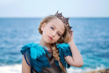 portrait of a young princess girl in a crown and azure dress is tilted her head and looks tenderly © Tatsiana
