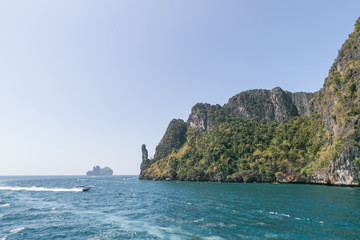 scenic view of rocky formations covered with green plants, blue sky and ocean, phi phi islands