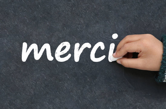 Main d'enfant &eacute;crivant merci &agrave; la craie sur une ardoise