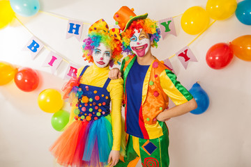 Obraz na płótnie Canvas Clowns are a boy and a girl in bright costumes at the child's birthday. The explosion of emotions and the fun of the circus