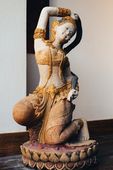 Old mortar statue of woman wearing thai dress kneeling on the lotus at the home, Vintage, Thailand name is Thokkathan-Mother Earth Squeezing Her Hair