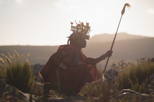 Maasai man in traditional clothing sitting at countryside