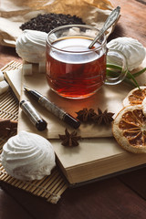 A cup of hot tea, Spices, Sweets, Envelope with pen on a wooden table